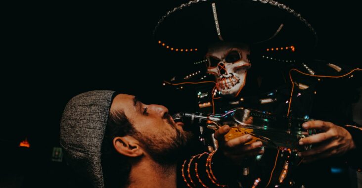 Un squelette mexicain sert un verre d'alcool à un homme lors d'une soirée d'Halloween