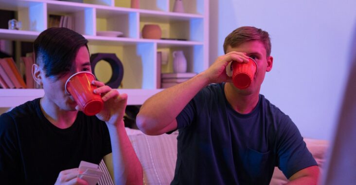 Deux hommes boivent leur verre après avoir perdu au petit bac à boire